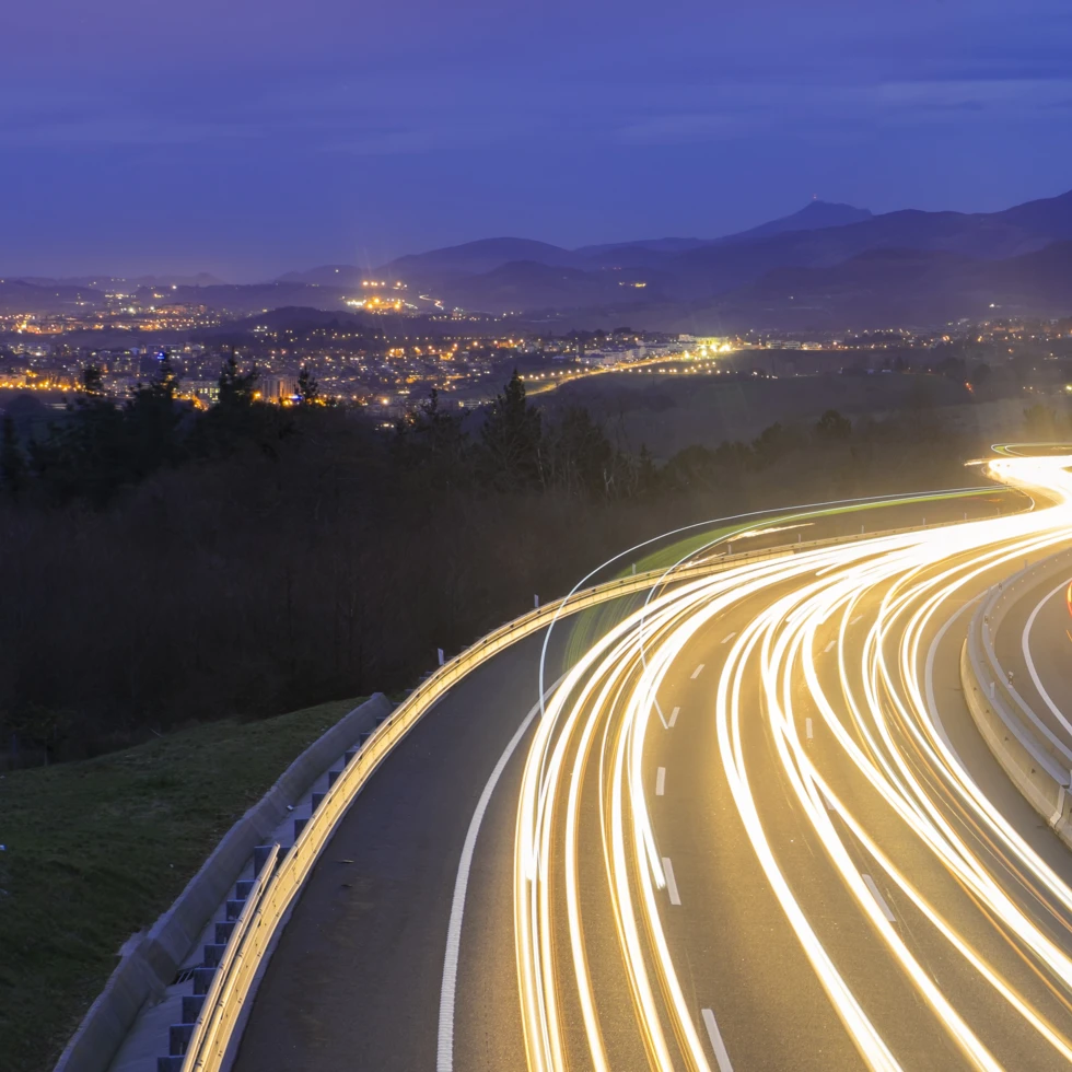 Żółta autostrada ciągnąca się aż po horyzont z wieloma pasami ruchu i słupami elektrycznymi. Droga o ograniczonym dostępie dla użyteczności publicznej.