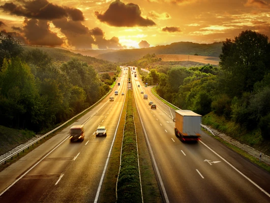 Żółta autostrada z pojazdami poruszającymi się po drodze z ograniczonym dostępem. Powierzchnia asfaltowa z poboczem do nagłych zatrzymań.