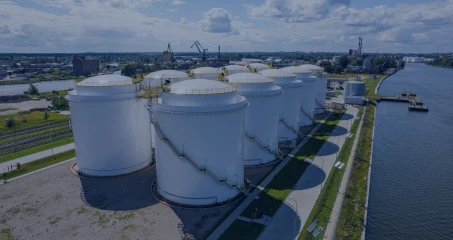 Wysoka zbiornik na składowanie zboża odbijający się w wodzie na zewnątrz fabryki w otoczeniu przemysłowym. Jasny i pogodny dzień. Atmosfera przemysłowa.